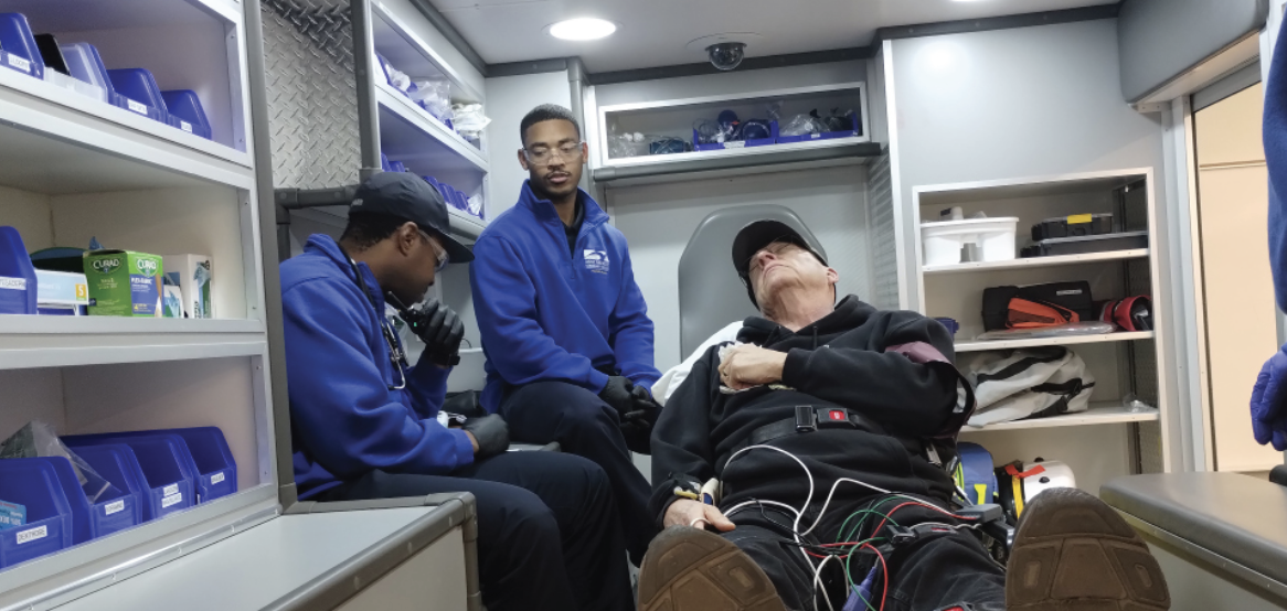 Paramedic students Jermaine Mills, left, and Jordan Hopkins, center, pretend to treat actor Steve Hopp.
